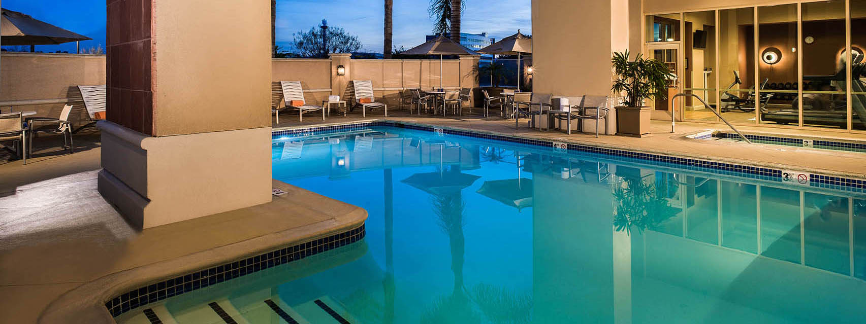 Outdoor heated pool and patio seating area at Hilton Santa Clara near the fitness center